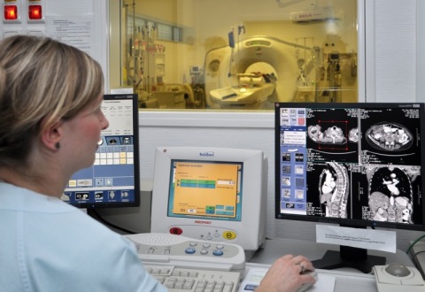MTRA bedient Konsolen im Schaltraum eines Computertomographen