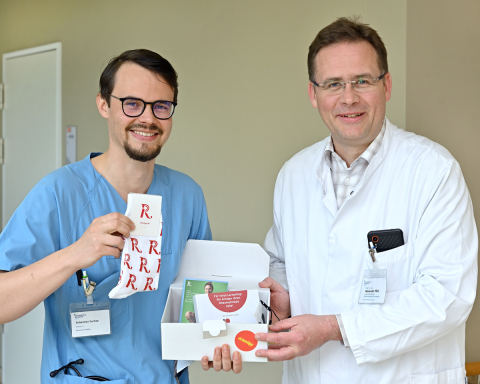 Prof. Dr. Alexander Pfeil übergibt das Care-Paket an Sebastian Sachse auf Station A140.